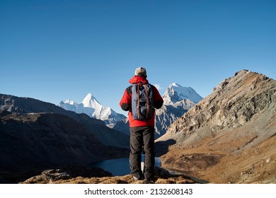 rear view of asian man backpacker male hiker looking at mountains in yading national park, daocheng county, sichuan province, china - Powered by Shutterstock