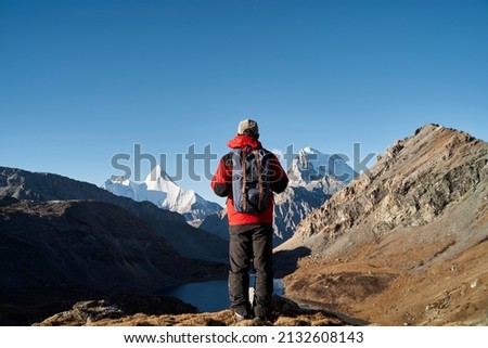 rear view of asian man backpacker male hiker looking at mountains in yading national park, daocheng county, sichuan province, china