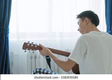 Rear View Of Asian Man Play Guitar At Home, Feel Relaxing