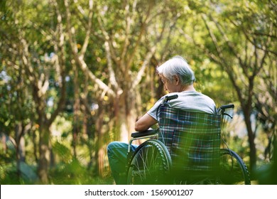 rear view of asian old man sitting in a wheelchair with head down looking sad and depressed