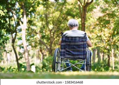 Rear View Of Asian Old Man Sitting Outdoors In Wheel Chair, Head Down