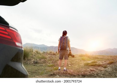 rear view of an asian photographer traveling by car looking at view in the morning sunlight with camera in hand
