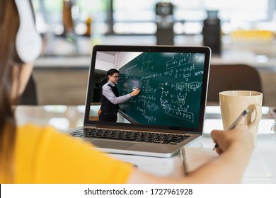 Rear View of Asian student learning with teacher over the physics formular in thai laguage on black board via video call conference when Covid-19 pandemic, education and Social distancing concept
