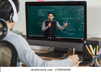 Rear View Of Asian Student Learning With Teacher Over The Physics Formular In Thai Laguage On Black Board Via Video Call Conference When Covid-19 Pandemic, Education And Social Distancing Concept