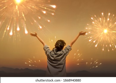 Rear view of Asian woman with a happy expression celebrating the new year with fireworks on the sky. Happy New Year 2021