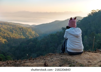 Rear view of asian woman sitting on the ground looking on the view of beautiful nature on the top of mountain. People enjoying with panoramic view in the morning time. - Powered by Shutterstock