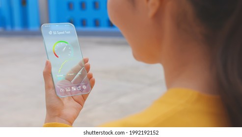 rear view of asian woman use transparent screen 5G smartphone to check the high speed of connection outdoor