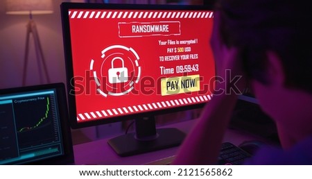 rear view of asian worried young man looking at computer with ransomware attack words on the screen when he mined at home in the evening