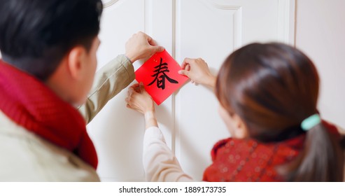 rear view of asian young couple paste up character of word meaning spring on the door to celebrate chinese new year - Shutterstock ID 1889173735