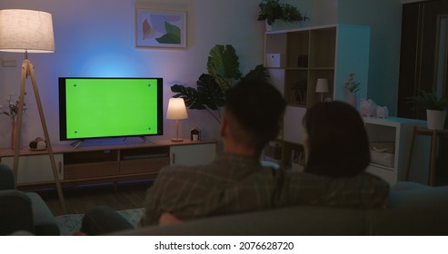 rear view of Asian young couple are watching green chroma key screen TV and having fun while sitting on couch at night in the living room - Shutterstock ID 2076628720