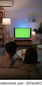 rear view of Asian young couple are watching green chroma key screen TV and having fun while sitting on couch at night in the living room - Shutterstock ID 2076628726