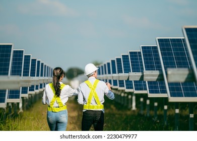 Rear view of Asian Young Inspector Engineer man and female colleague walking between row of solar panel while checking operation in solar station - Powered by Shutterstock