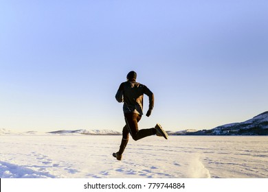 Rear View Athlete Runner Running On Snow In Black Sport Clothes