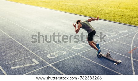 Rear view of an athlete starting his sprint on an all-weather running track. Runner using starting block to start his run on race track.