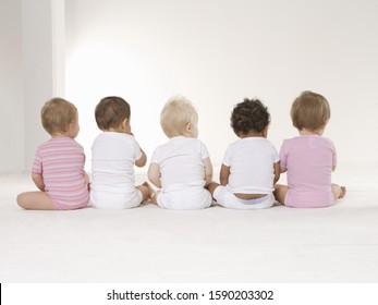 Rear view of babies sitting on floor