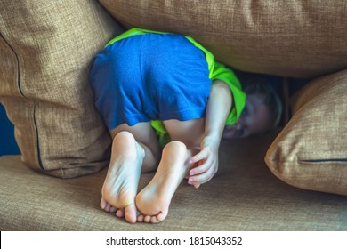 Rear View, Back Butt Legs Feet Of A Child Hiding Under A Pillow, Offended Boy In Bad Mood Or Playing. Funny Photo. Family Relationship, Childhood Problems And Behaviour Concept, Education Psychology