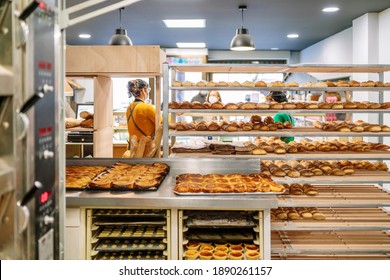 Rear view of a bakery with sales clerks selling bread to customers and carts with loaves and cakes fresh from the oven are seen and all are wearing face masks due to the covid19 coronavirus pandemic - Powered by Shutterstock