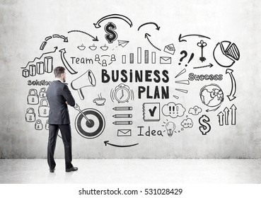 Rear View Of A Bearded Businessman Looking At A Business Plan Sketch Depicted At A Concrete Wall. Concept Of Strategy Development