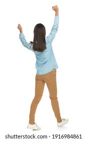 rear view of a beautiful casual woman walking with her hands up in the air against white background