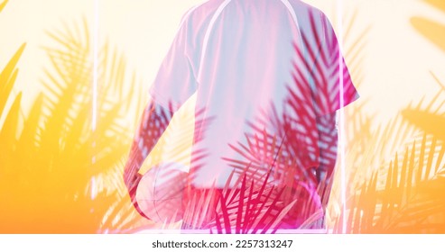 Rear view of biracial female rugby player with ball standing over illuminated rectangle and plants. Copy space, composite, sport, competition, shape, nature, playing, match and abstract concept. - Powered by Shutterstock