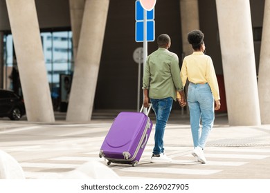 Rear View Of Black Family Couple Walking With Travel Suitcase At Modern Airport Terminal Outdoors. Full Length Shot Of Unrecognizable Tourists Traveling On Vacation Together