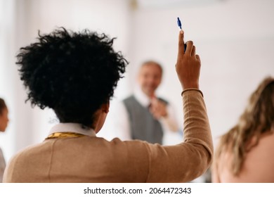 Rear View Of Black Student Raising Her Hand To Answer A Question During A Class At Lecture Hall.