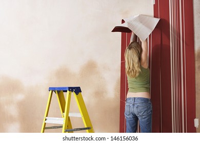 Rear View Of A Blond Young Woman Hanging Wallpaper