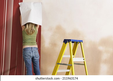 Rear View Of A Blond Young Woman Hanging Wallpaper