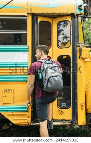 Rear view of a boy with a backpack entering a school bus