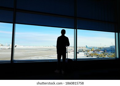 Rear View A Boy Holding Luggage And Overseeing Busy Airport. Holiday, Travel, Vacation Trip After Covid-19 Pandemic Lockdown Concept.