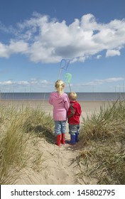 Rear view of brother and sister holding fishing nets on beach