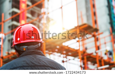 Rear view of builder inspector checking  construction site works.