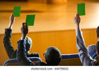 Rear view of business executives show their approval by raising hands at conference center - Powered by Shutterstock