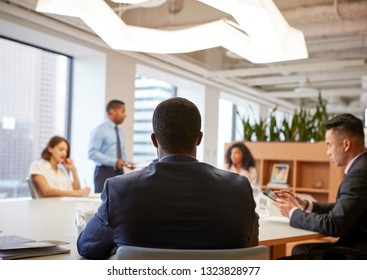 Rear View Of Business Professionals Meeting Around Table In Modern Office