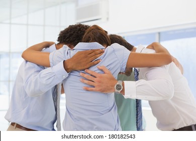 Rear View Of Business Team With Heads Together Forming A Huddle