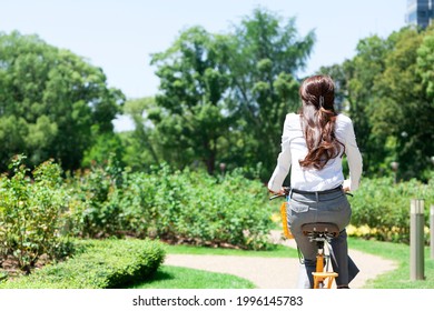 Rear view of a business woman riding a bicycle - Shutterstock ID 1996145783