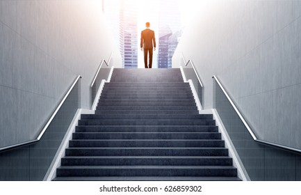 Rear view of a businessman ascending a staircase in a city. Cityscape is in the background. Toned image