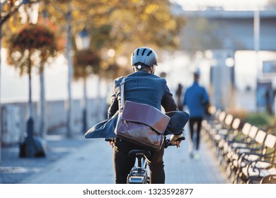 A rear view of businessman commuter with electric bicycle traveling to work in city.