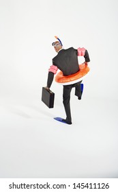 Rear View Of A Businessman In Flippers; Inflatable Rubber Ring; Snorkel And Goggles Holding Briefcase Against White Background