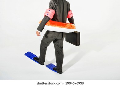 Rear View Of A Businessman In Flippers, Inflatable Rubber Ring Holding Briefcase Against White Background