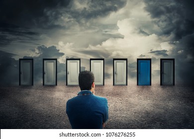 Rear view of a businessman in front of many doors choosing the one different colored. Difficult decision, concept of the important choice in life, failure or success. The ways to unknown future, busin - Shutterstock ID 1076276255