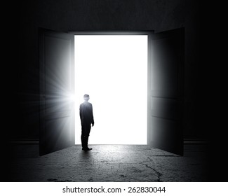 Rear View Of Businessman Standing In Light Of Opened Door