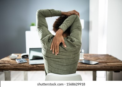 Rear View Of A Businessman Stretching His Arms In Office