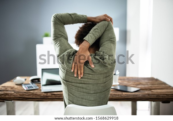 Rear View Of A Businessman Stretching His Arms In Office
