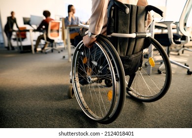 Rear view of businesswoman with disability uses wheelchair while going through the office.