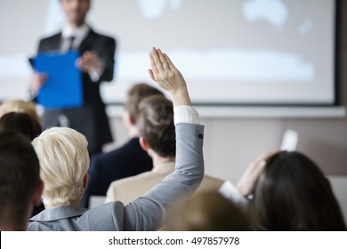 Rear view of businesswoman raising hand during seminar - Shutterstock ID 497857978