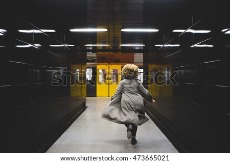 Rear view of businesswoman running to catch the subway train, which is already leaving the underground station. 