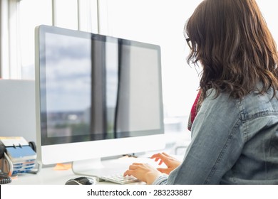 Rear View Of Businesswoman Using Desktop Computer In Creative Office