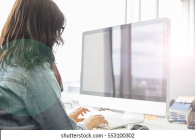 Rear View Of Businesswoman Using Desktop Computer In Creative Office