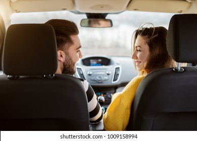Rear view in a car of beautiful young happy love couple looking each other.